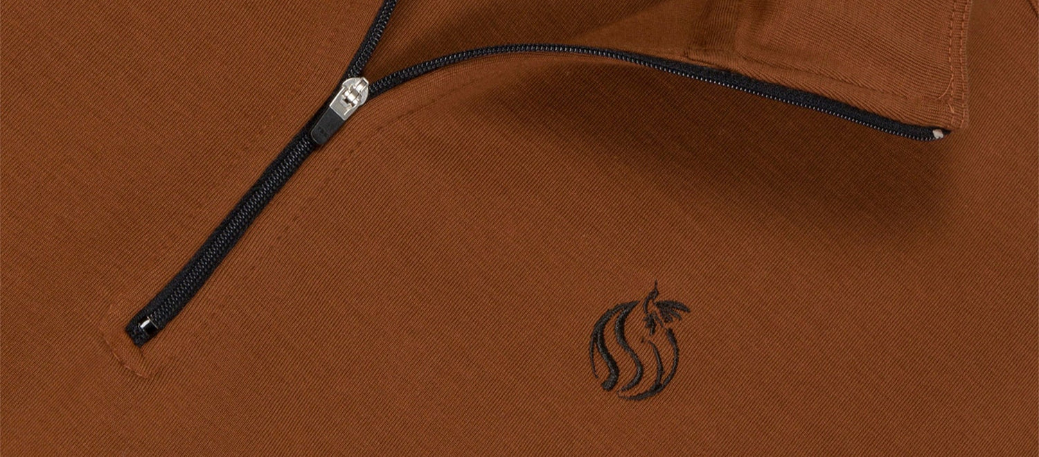 Detail of black zipper and embroidery on brown half zip