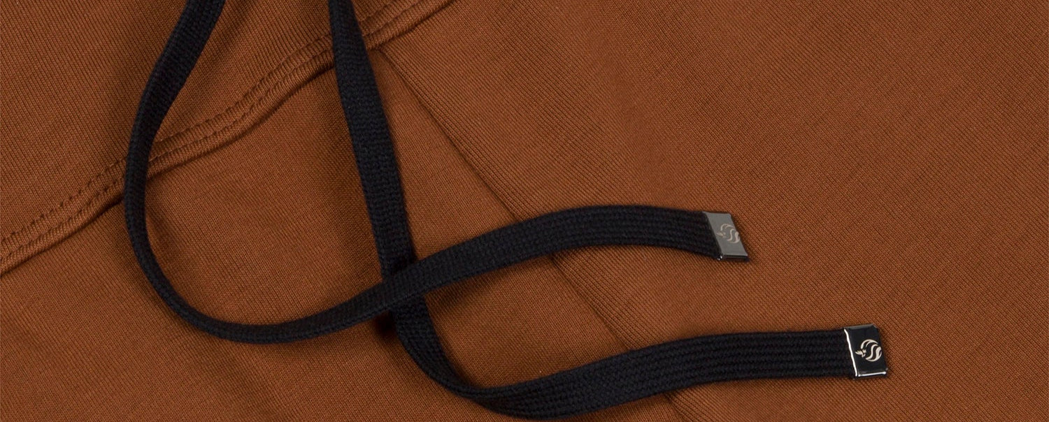 Detail of black drawstrings on brown joggers