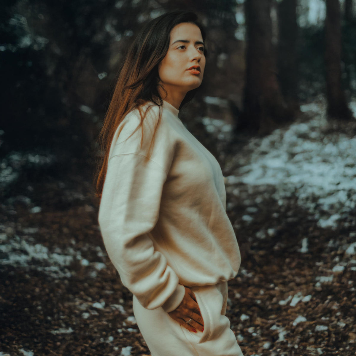 Female model poses with on beige crewneck and sweatpants